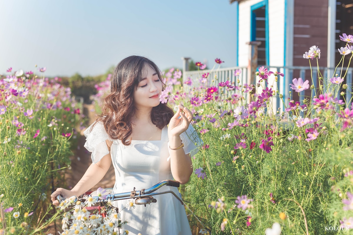 woman in white dress standing on flower field during daytime